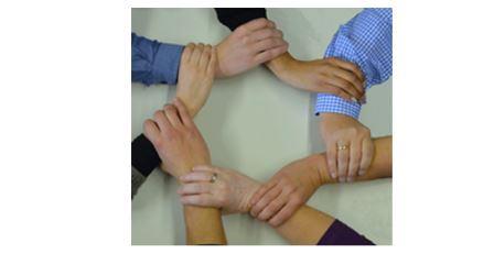 Foto mit Handkreis aus sieben sich jeweils am Unterarm fassenden Händen